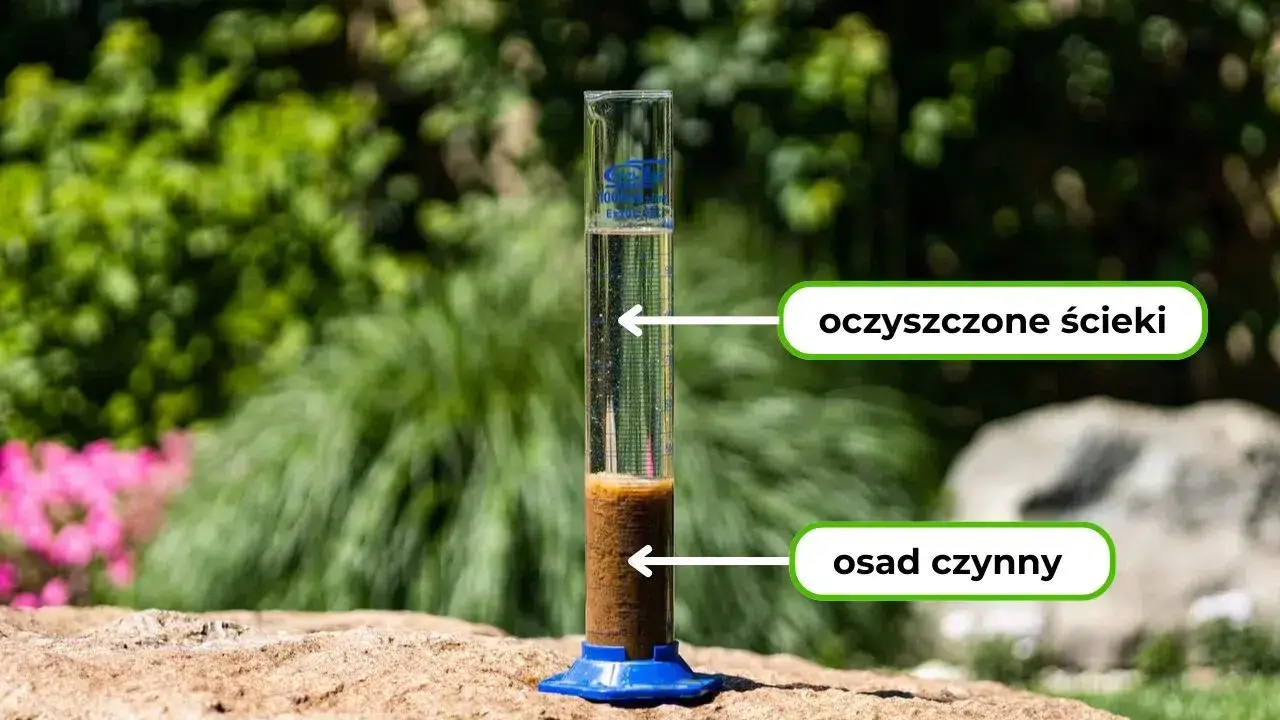 Cylinder z oczyszczonymi ściekami i osadem czynnym ustawiony na kamieniu w ogrodzie